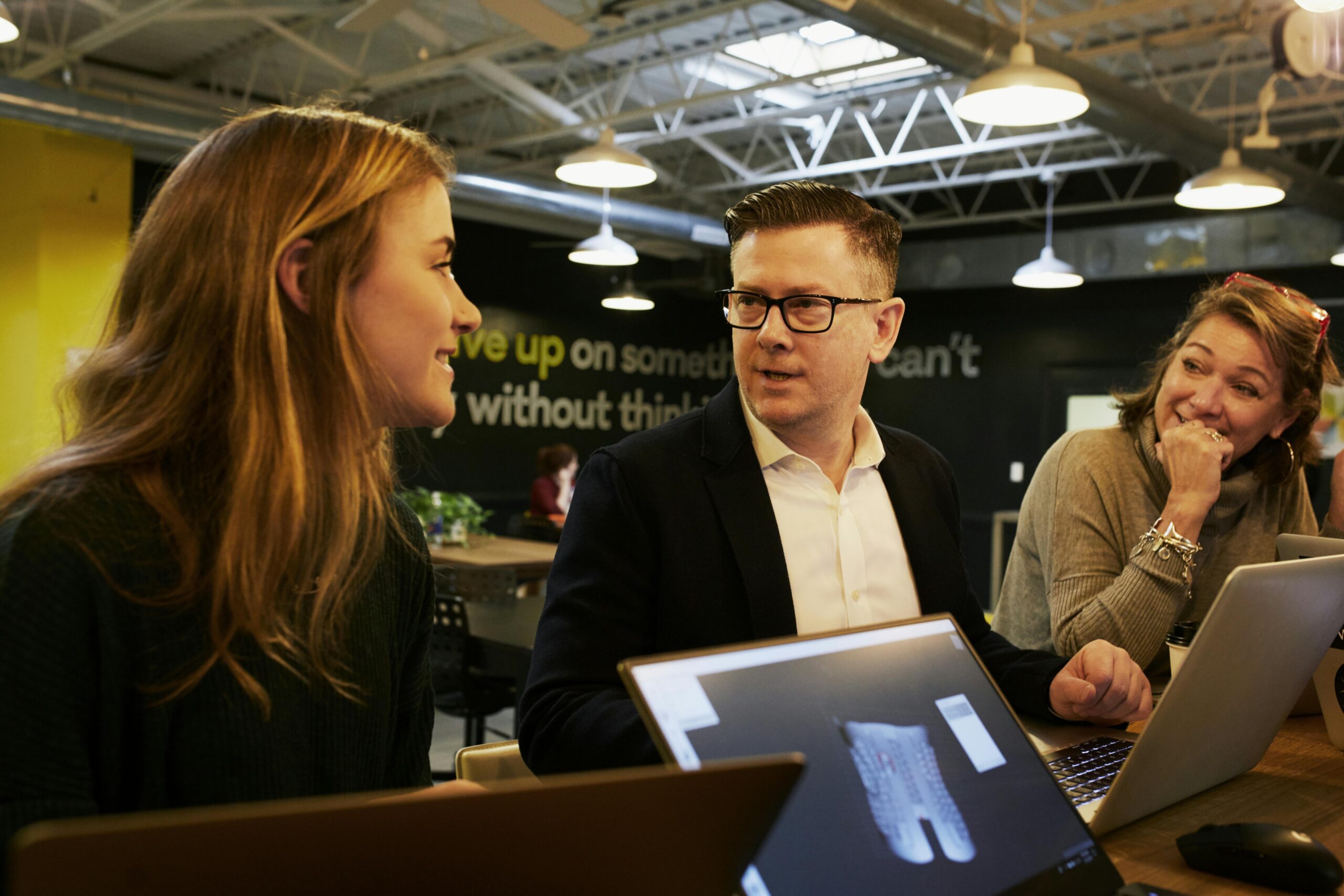 Three colleagues engaged in a lively discussion in a modern office space, fostering teamwork.